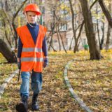 boy in orange and black jacket standing on brown dried leaves during daytime